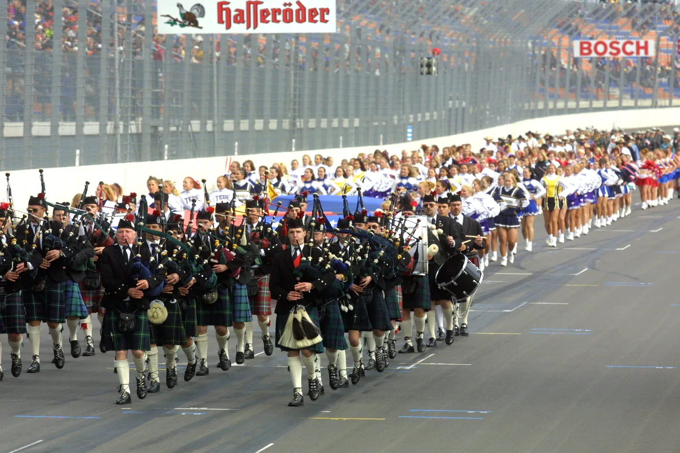 Pipe band and cheerleaders parading on the track in front of the grandstands before a race